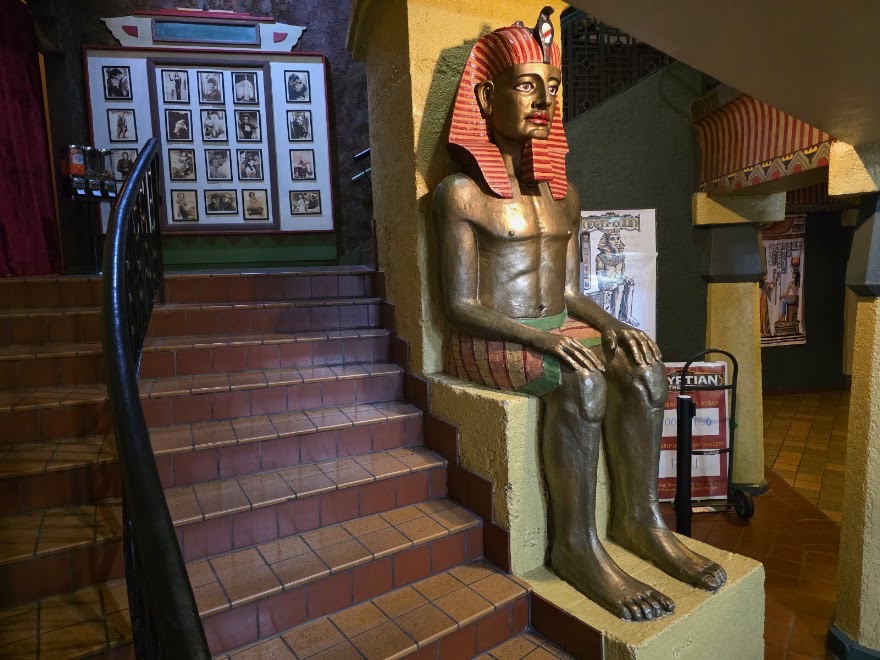A seated pharaoh statue beside the staircase in the Egyptian Theatre lobby.